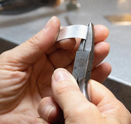 Silversmith bending silver by hand with pliers